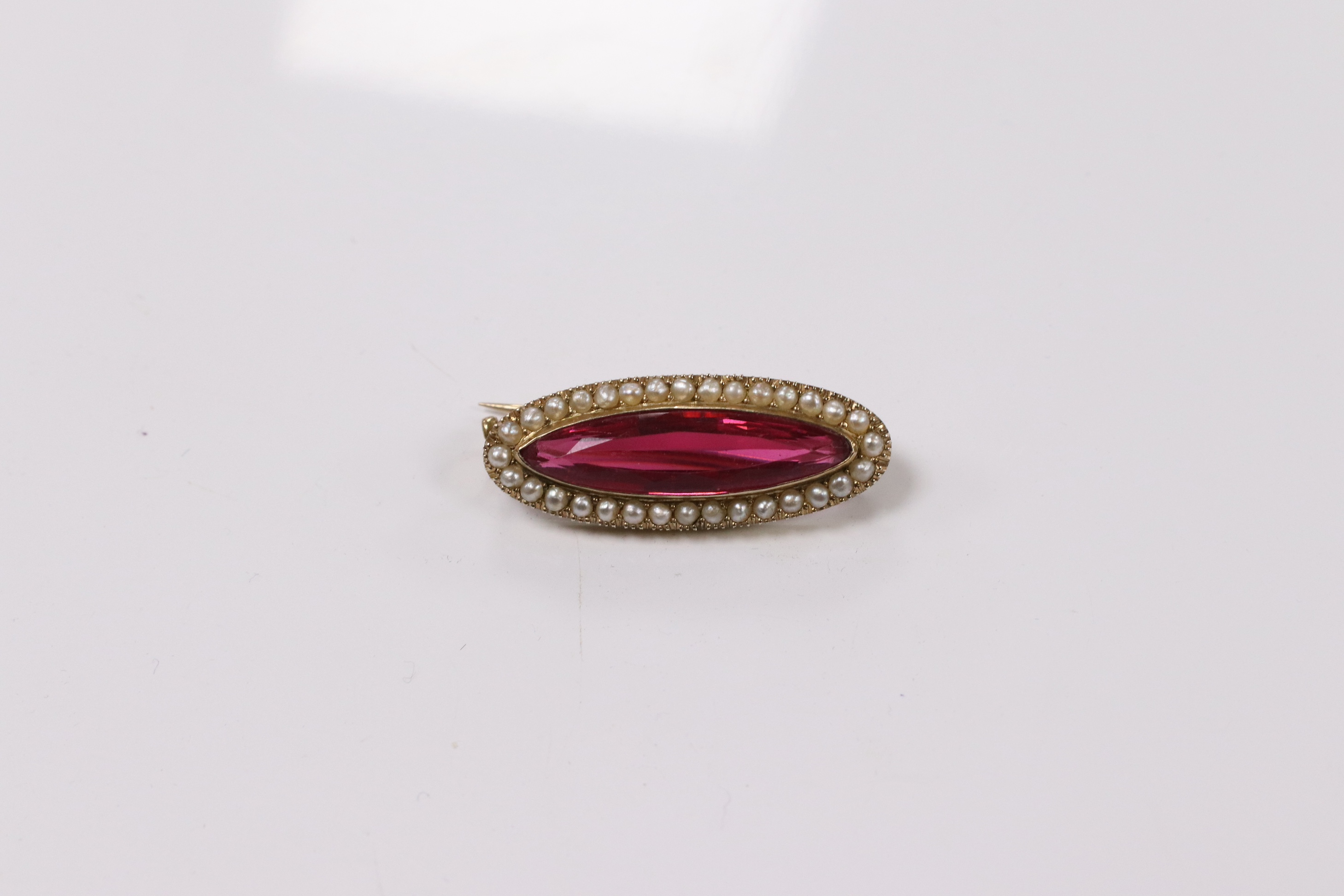 A 9ct, red paste and seed pearl set navette shaped brooch, 31mm, gross weight 4.2 grams. Condition - good